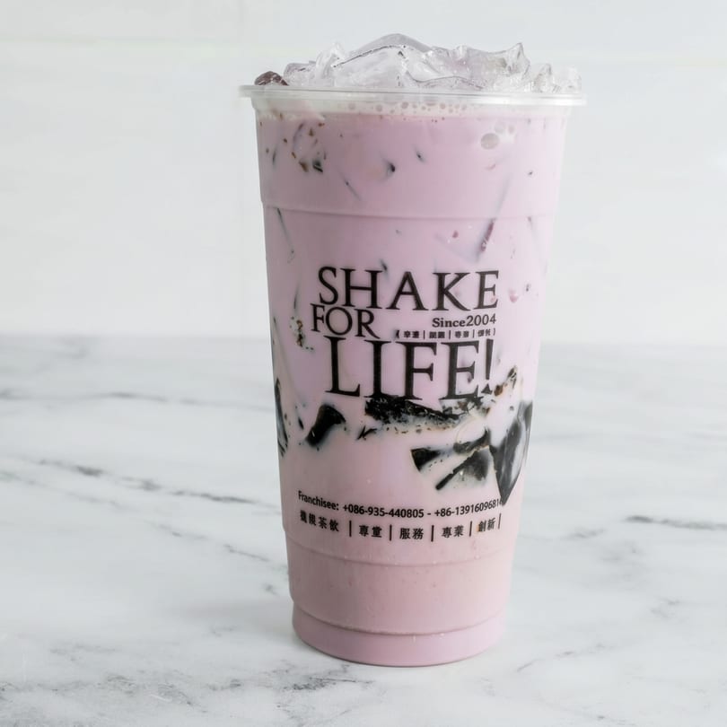 A Shake for Life! bubble tea with purple liquid, black jelly, and ice on a marble surface.