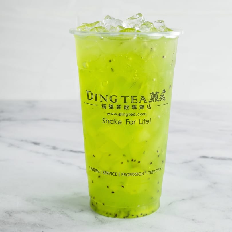 A Ding Tea kiwi fruit drink with ice and kiwi seeds in a clear plastic cup.