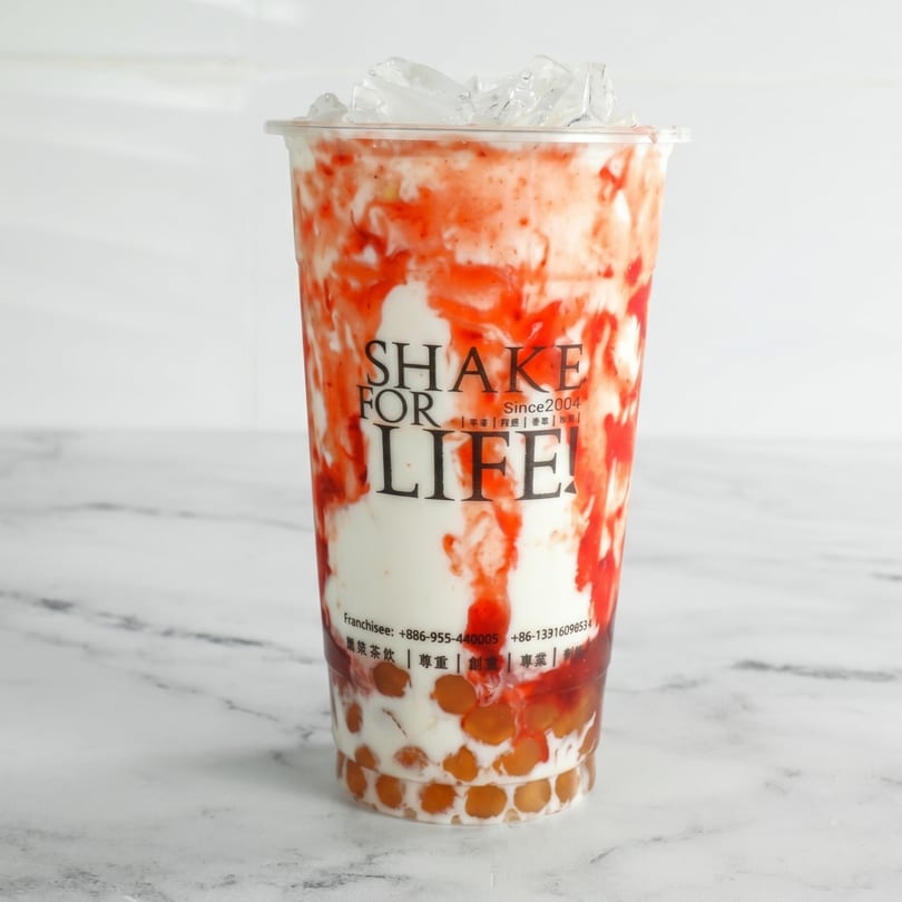 A Shake for Life! strawberry and cream drink with boba and ice on a white marble surface.